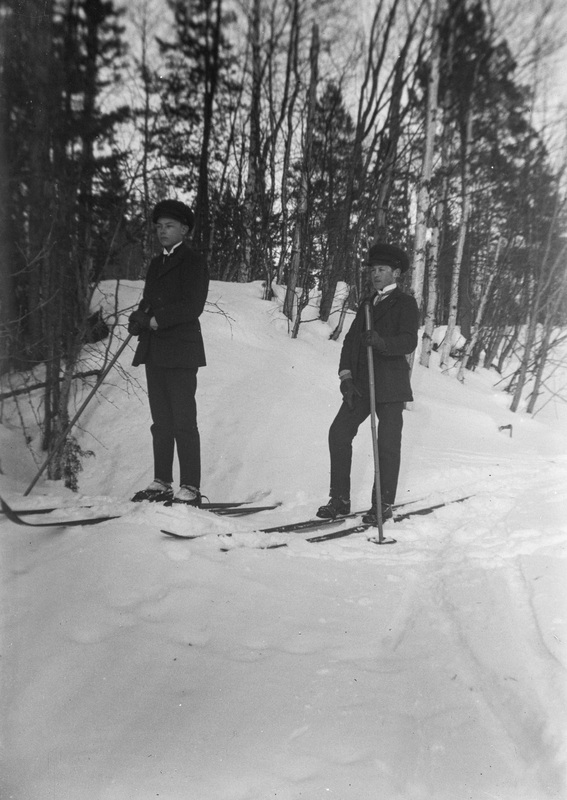 Två pojkar på skidor, obs med en lång skidstav ...
