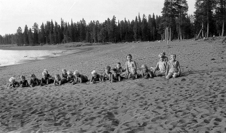 En grupp med barn, sittande på en strand.