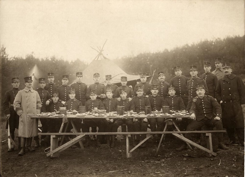 Militärer vid dukat matbord framför ett tält.