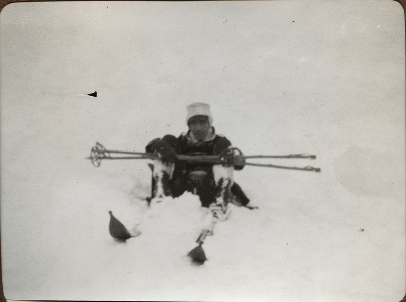 Soldat som sitter i snön med skidor på sig.