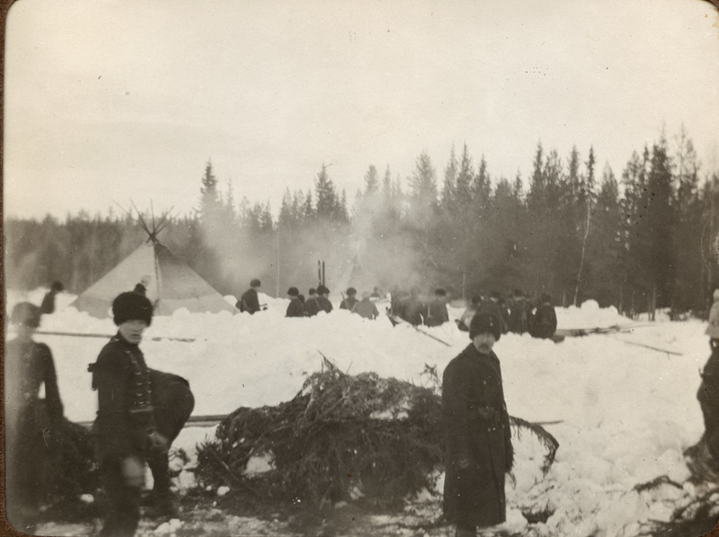 Militärt tältläger i snöig skogsbygd.