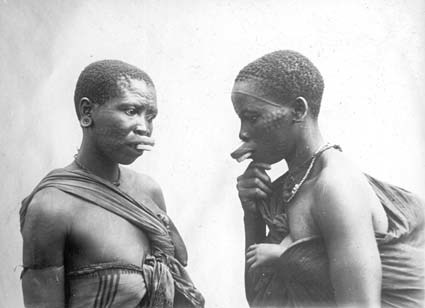 Makondekvinnor med prydnadsärr och läpp-plugg.