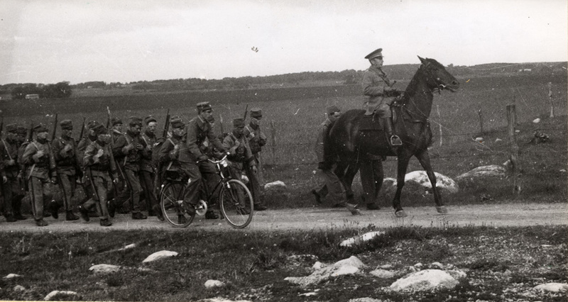 Soldater på marsch anförda av ett befäl till häst.