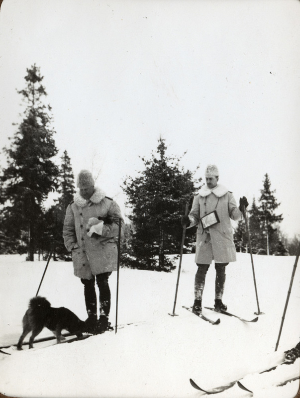 Två militärer på skidor tillsammans med hund.