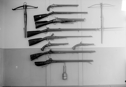 Gevär, pistoler och armborst upphängda på en vägg.
