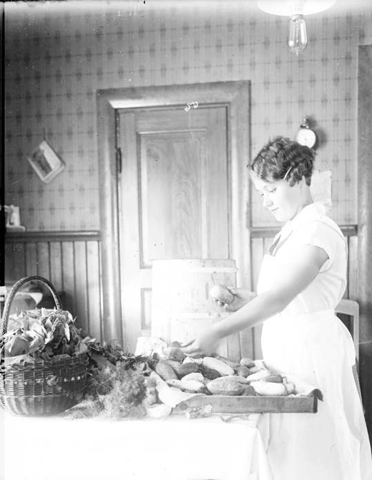 Bilden visar en kvinna som arbetar i köket, hon...