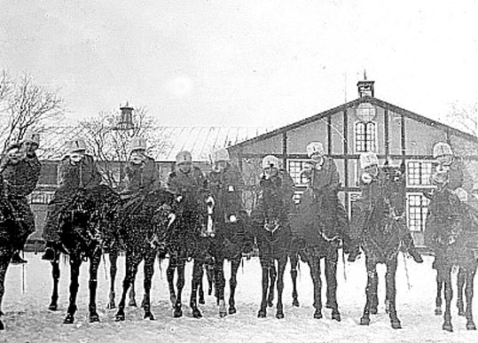 Bilden visar 9 elever till häst framför ridhuse...