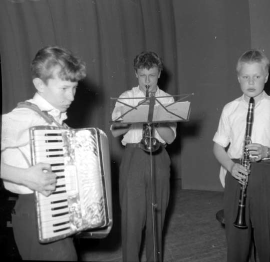 Tre pojkar spelar på sina instrument, från väns...
