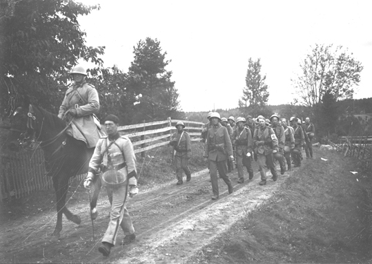 Militärer på marsch med en beriden häst i täten.