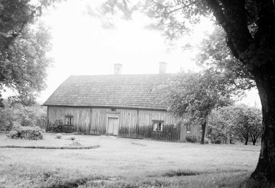 Bilden visar ett hus med stående träpanel, brut...