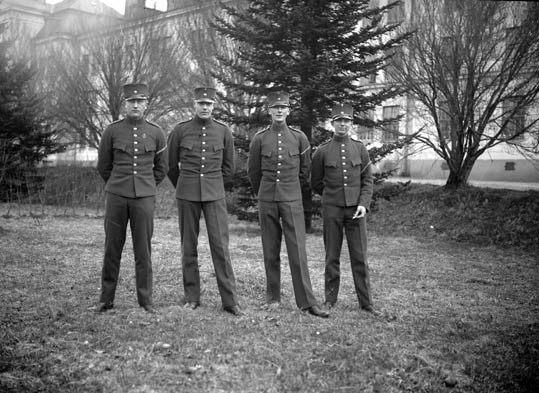 Fyra stiliga uniformsklädda  herrar står utanfö...